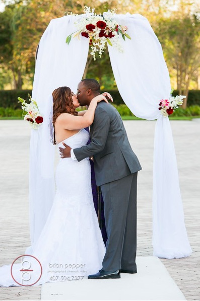 Rosen Shingle Creek Resort Wedding with Ivory and Berry Mary and Brandon Ceremony A Chair Affair garden wedding arch kiss