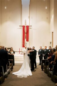 bride being handed off to her groom by her father at the end of the aisle