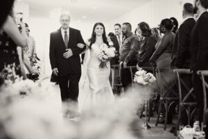 Bride walking down aisle with father during wedding ceremony at Grand 721. New Smyrna wedding rentals