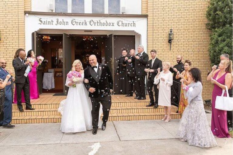 The bride and groom exiting the church surrounded by bubbles blown by their guests.