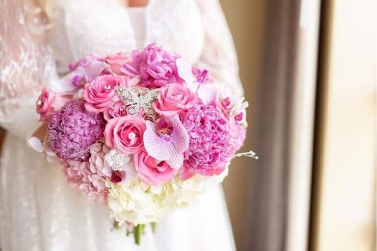 Up close picture of bride in her wedding dress while holding her pink flower bouquet.