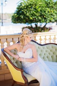 The bride sitting on a chair in wedding dress with her head turned to the side to display fishtail braid