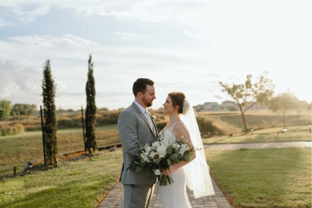 The bride and groom gazing at each other outside the winery, with the sun shining brightly in the background.
