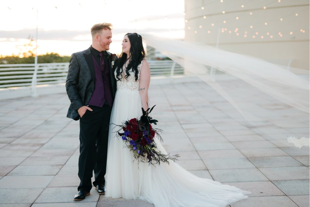 The bride and groom captured in a picture outside on the rooftop with the sun setting in the bachground.