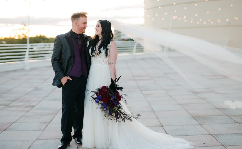 The bride and groom captured in a picture outside on the rooftop with the sun setting in the bachground.