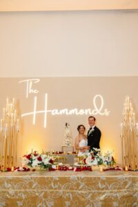 The bride and groom in front of neon sign