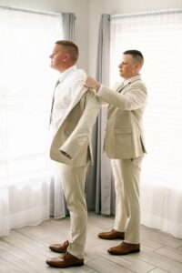 The groom being helped into his suit jacket by one of his groomsmen