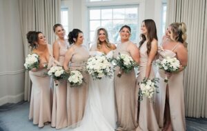 The bride and her bridesmaids in their gowns before the ceremony holding bouquets with smiles on their faces