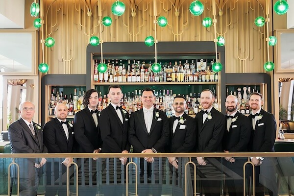 The groom and his groomsmen standing side by side captured in front of a bar in the Don Cesar Hotel