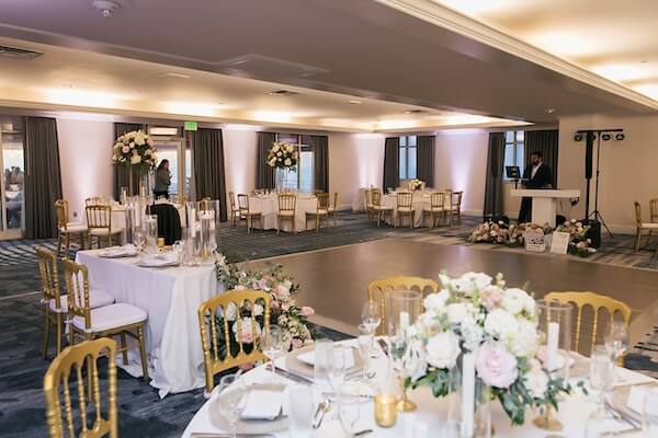 The wedding reception at the Don Cesar. Wedding rentals St. Pete provided Gold Napoleon Chairs and Champagne Glitter Glass Chargers. Tables throughout the rooms are also draped in white linens