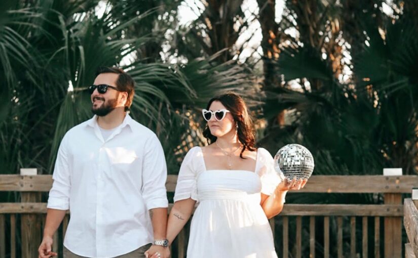 July monthly wedding winners photo captured on a bridge outdoors with trees in the background and both wearing sunglasses