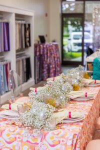 Open House table set up with retro linens, and clear ghost chairs provided from a chair affair seated around the table