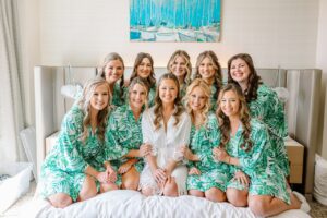The bride and her bridal party piled onto a bed and lined up to get a picture in their matching wedding day pajamas