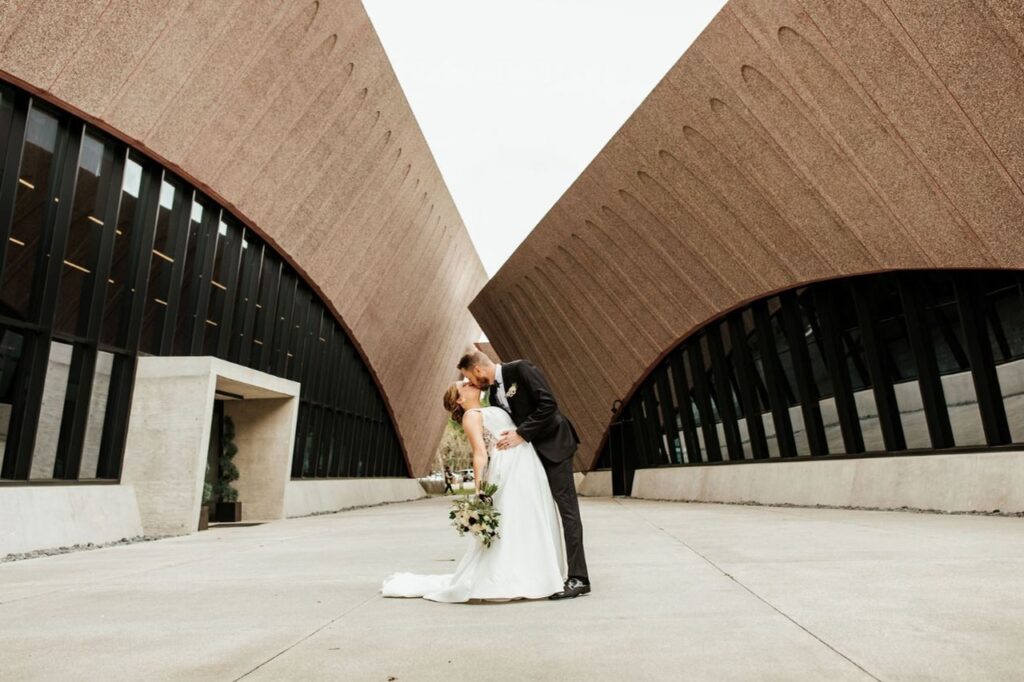 The groom dipping his bride and giving her a kiss outside the Winter Park Events Center venue