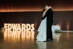 The bride and groom sharing their first dance on the dancefloor in front of a huge sign displaying their last name