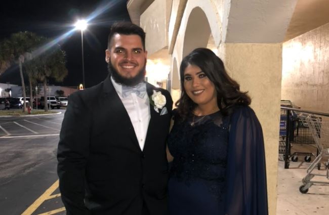 The September Monthly Wedding Winners in dressed up attire standing close to each other in a parking lot for a picture at night time