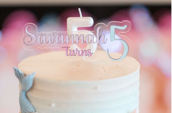 Savannah turns 5 topper on birthday cake next to number five candle and a mermaid tail