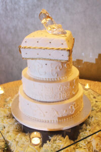 The three tier wedding cake with a glass slipper used as the wedding topper and the saying "They lived Happily Ever After" written on the side of the cake