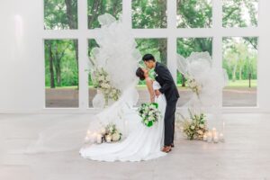 The first couple in front of the second ceremony set up with white tulle and flowers created as a center focal point