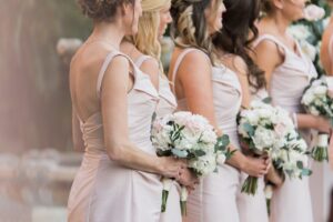 The bridesmaids standing in a line during the ceremony wearing their blush pink dresses