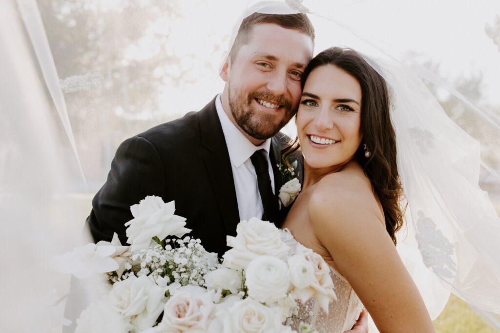 Olivia and Bryce McClanahan Wedding on 3/30/24. Bride and groom pictured under the brides veil