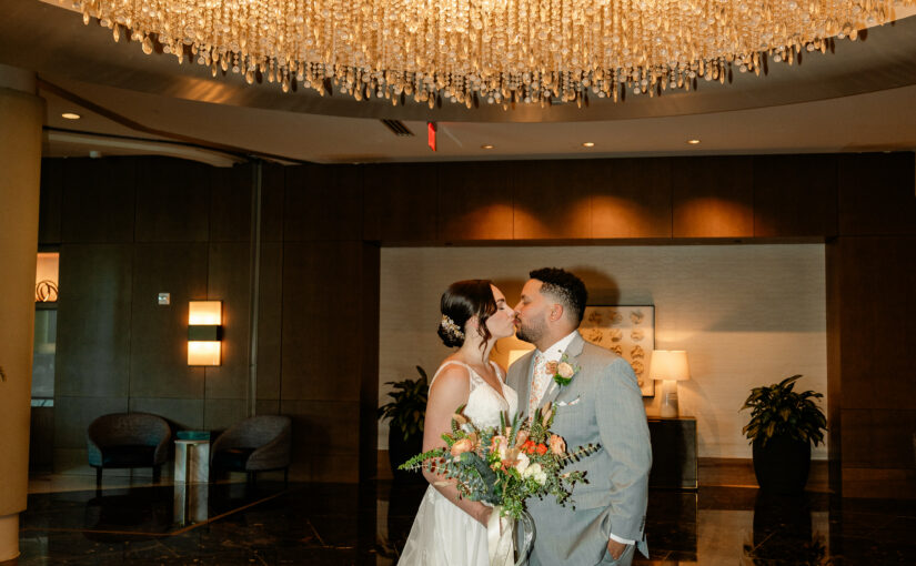 Bride and Groom kissing under gold chandelier at Hyatt Regency Orlando. Wedding Rentals Orlando.