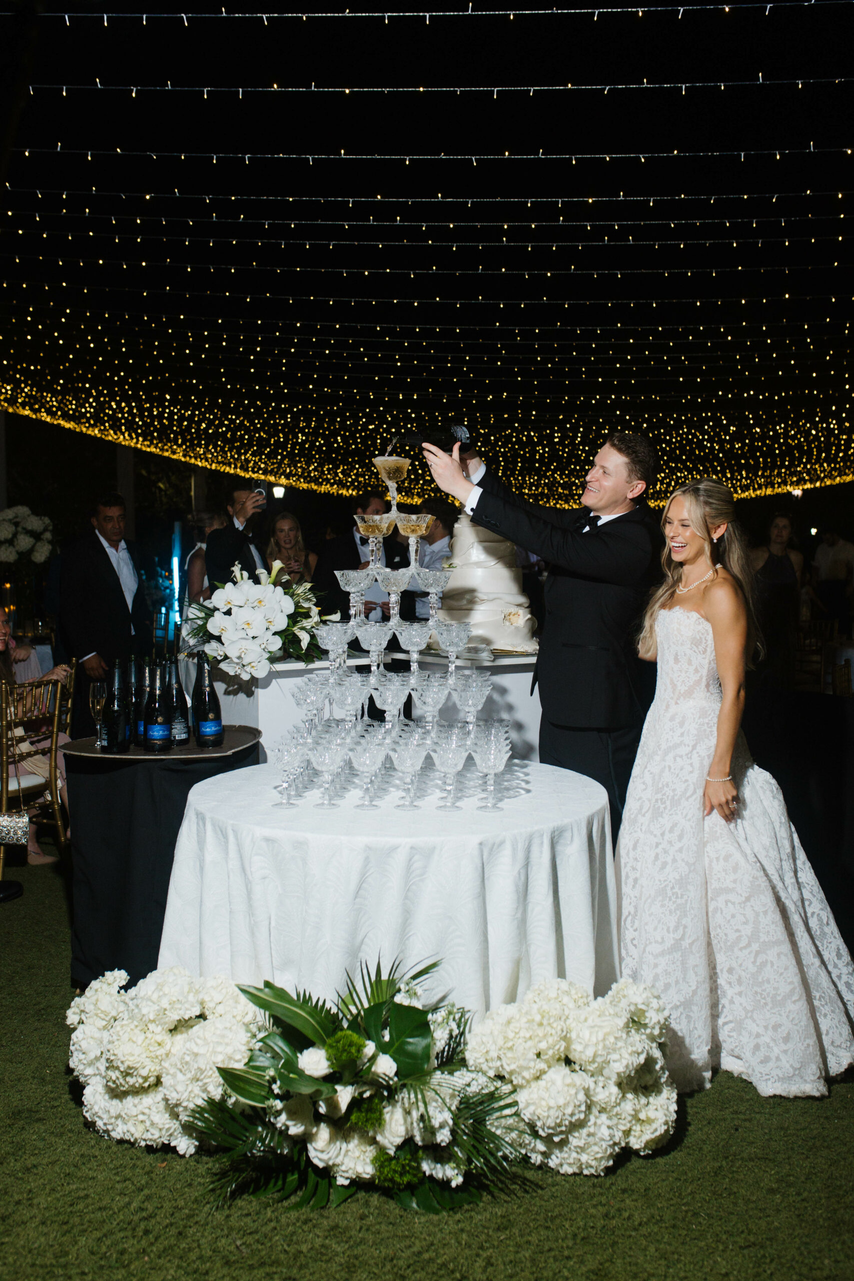 Bride and Groom pouring champagne into champagne tower of Grace Etched Champagne Coupes from A Chair Affair. Orlando Wedding Rentals. Central Florida Wedding Rentals