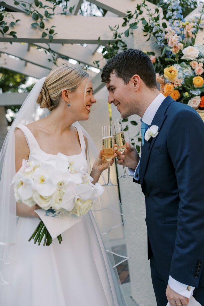Bride and Groom with champagne Glasses. A Sun-Drenched Celebration: Keaton and Matthew’s Stunning Wedding at The Vinoy