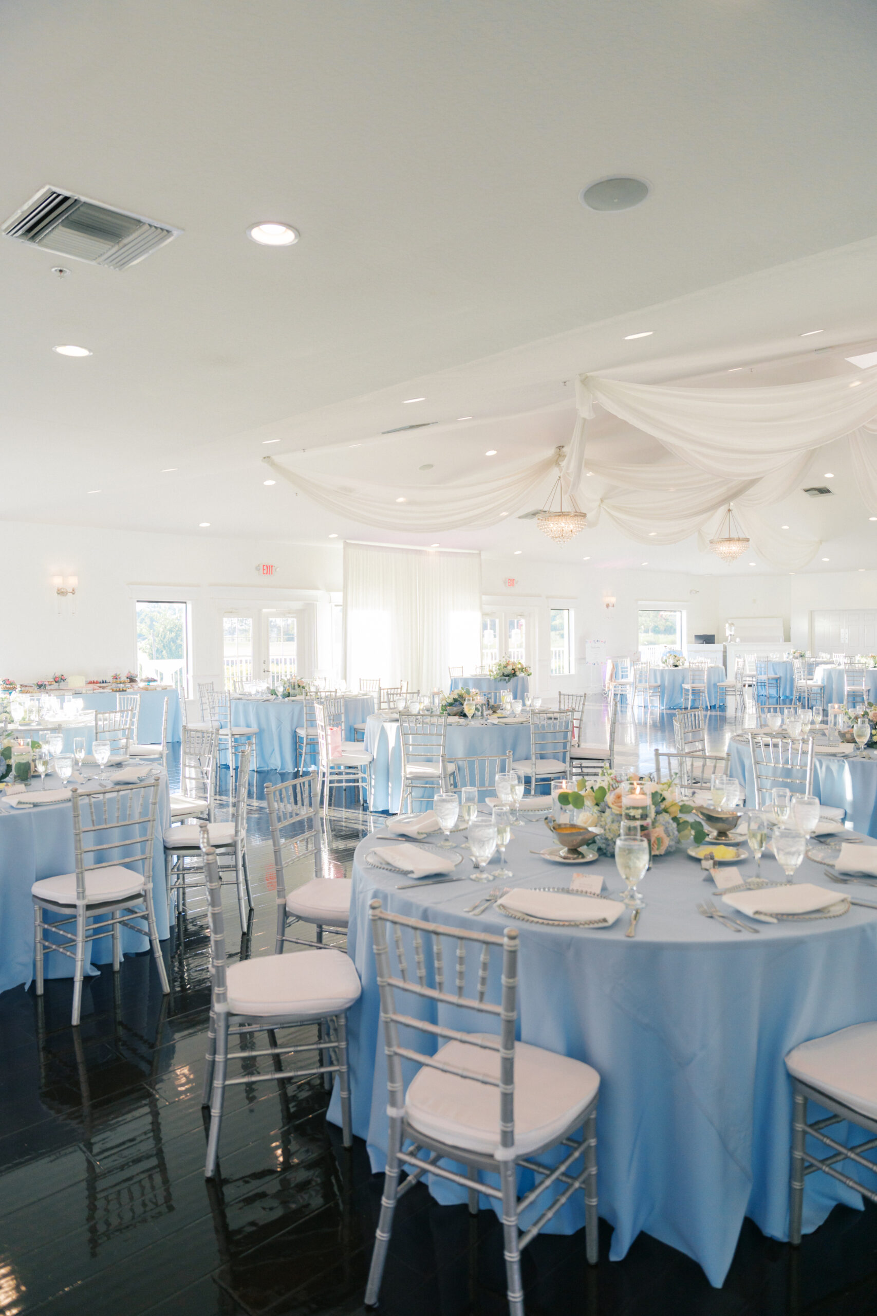 Tables with place settings and silver chiavari chairs, white chair pads and silver belmont chargers provided by A Chair Affair. St Petersburg Wedding Rentals. St Petersburg Weddings. Silver Chiavari Chairs. Chiavari Chair Rentals Florida. Florida Wedding Rentals.