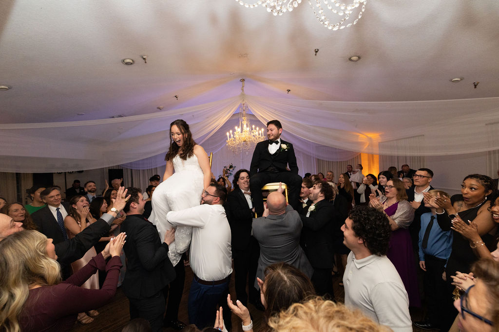 Bride and Groom lifted on chairs at reception at Highland Manor