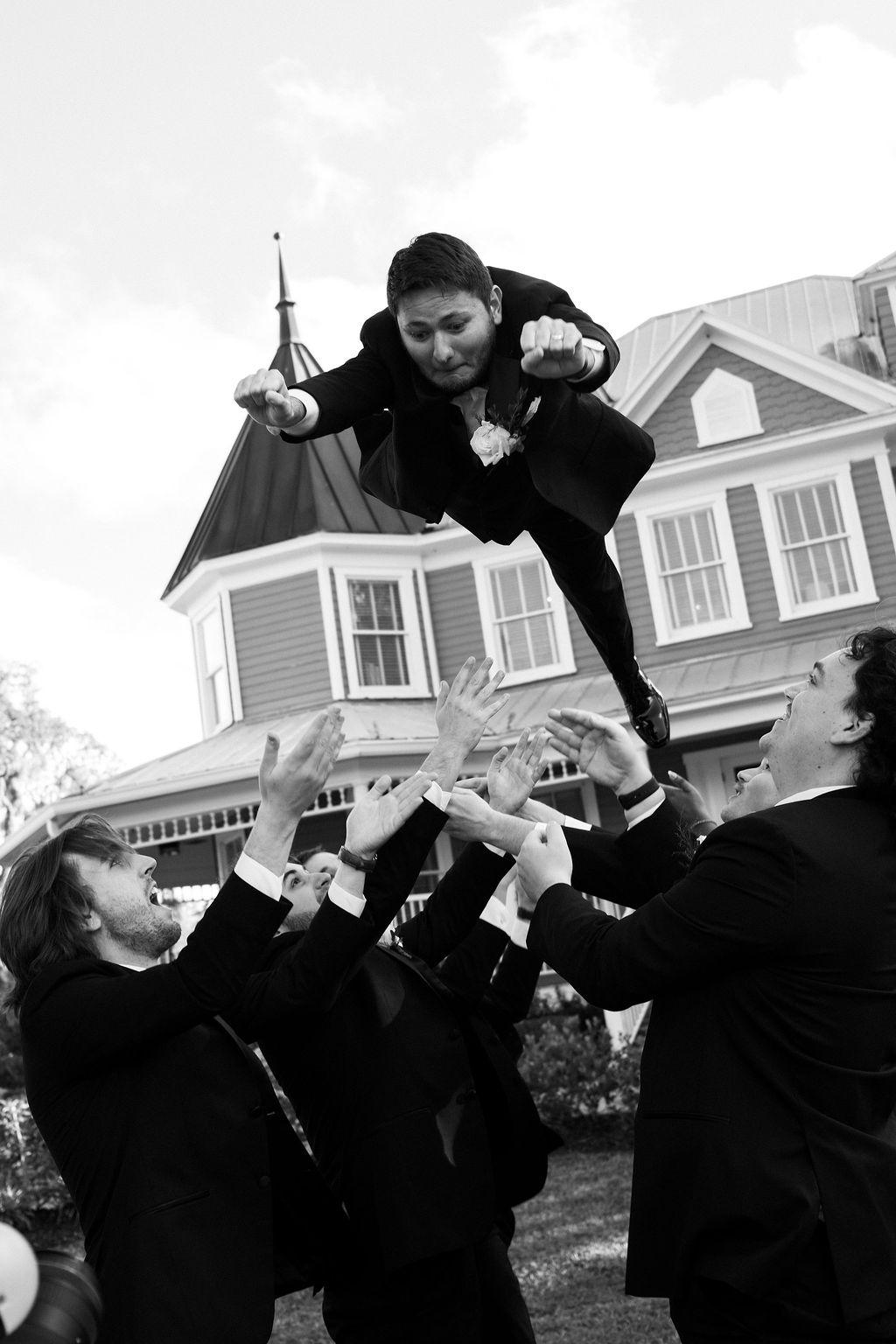 Groom being thrown in SuperMan pose by groomsmen
