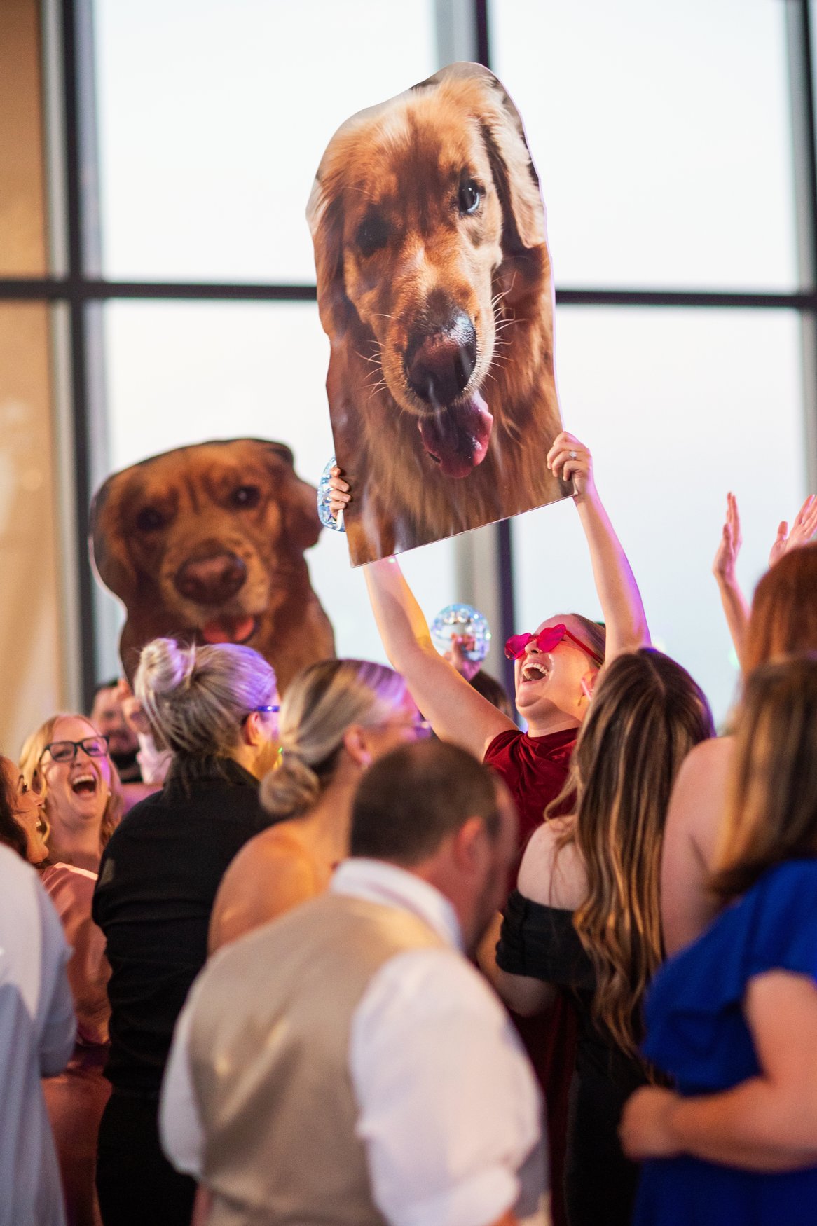 Large cutouts of golden retriever pup being held up on the dance floor