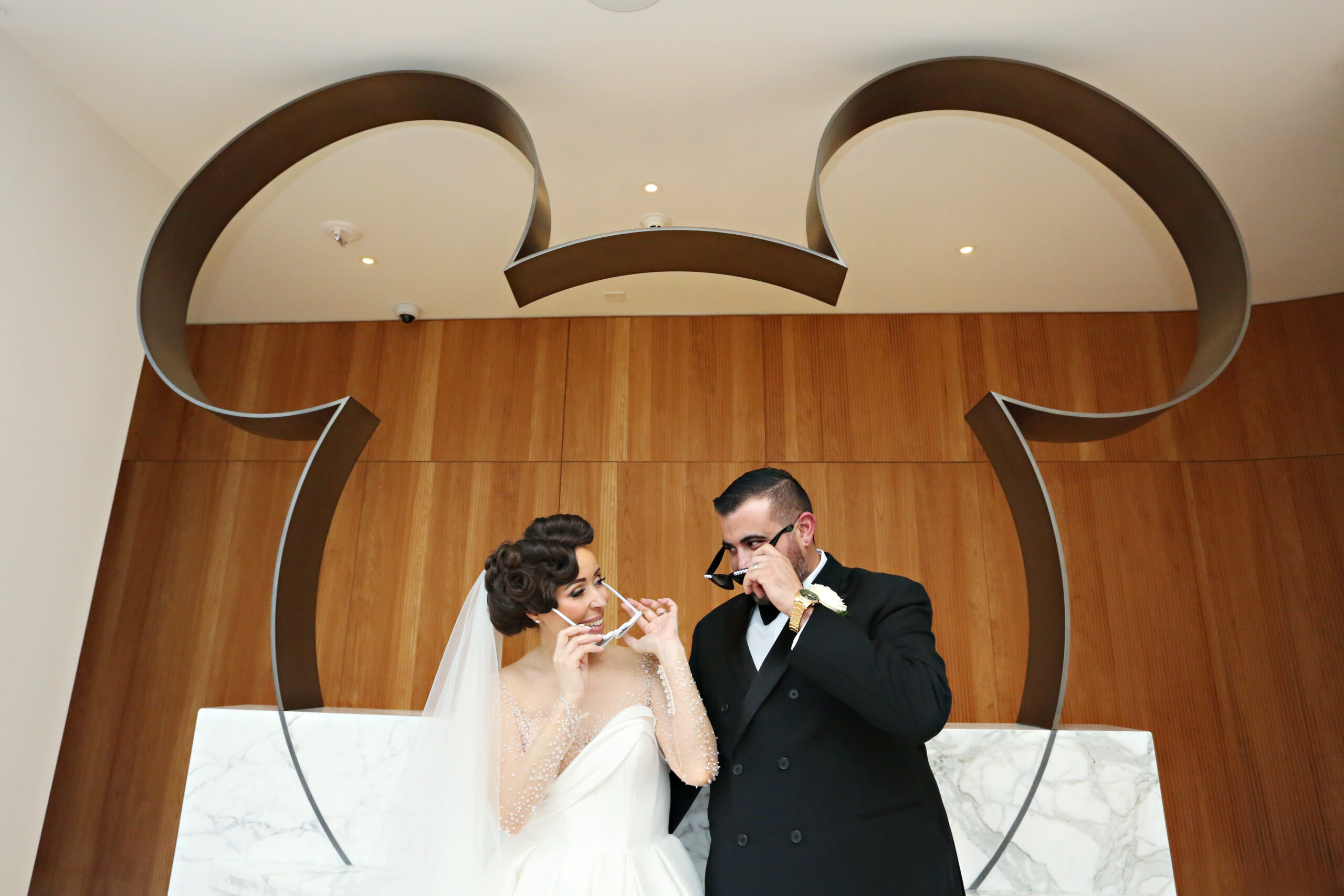 Bride and Groom with sunglasses in front of the mickey head.
